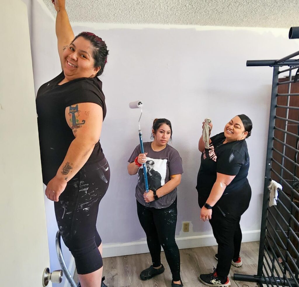 three women painting a wall